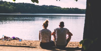 man and woman sitting together in front of lake